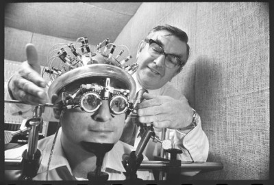 Researcher Derek Fender fitting apparatus for measuring brain waves on head of test subject at Caltech, 1974 <br /><br />Nate